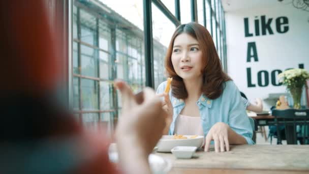 美丽快乐的亚洲女同性恋同志夫妇坐在一边吃着一盘意大利海鲜面条和法式薯条在餐馆或咖啡馆 而微笑着看食物 — 图库视频影像