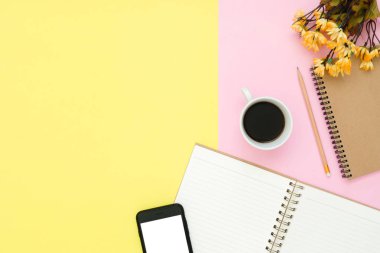 Ofis Masası adlı kullanıcının alanı - düz çalışma beyaz boş defter sayfası, kahve fincanı ve sahte telefon pastel arka plan üzerinde bir çalışma alanının en iyi görünümü yatırın. Pastel pembe sarı renk arka plan boşluk kavramı.