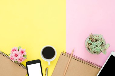 Ofis Masası adlı kullanıcının alanı - düz çalışma boş defter sayfası, kahve fincanı ve sahte telefon tablet pastel arka plan üzerinde yukarı çalışma alanının en iyi görünümü yatırın. Pastel pembe sarı renk arka plan boşluk kavramı.