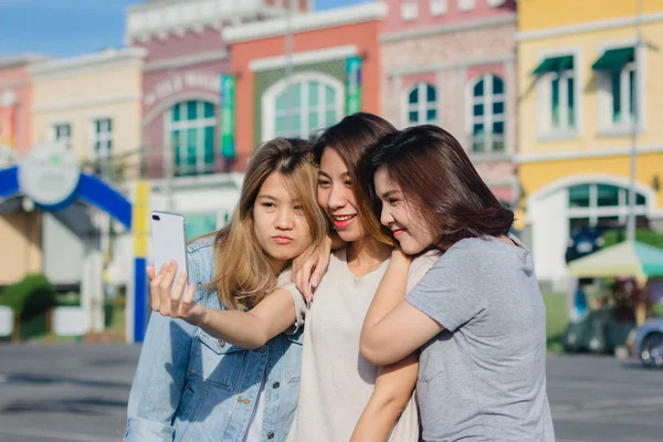 Attractive beautiful asian friends women using a smartphone. Happy young asian teenage at urban city while taking self portraits with her friends together with a smartphone.