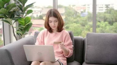Güzel Asyalı kadın kanepe oturma odasında yatan süre bilgisayar veya dizüstü bilgisayar kullanarak. Mutlu kadın evde alışveriş online satın alma. Yaşam tarzı kadına ev concept.