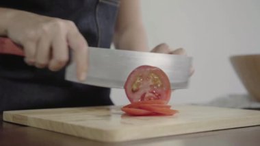 Salata sağlıklı yemek yapma ve mutfakta kesme tahtası üzerinde domates doğrama Şef kadının yakın çekim.