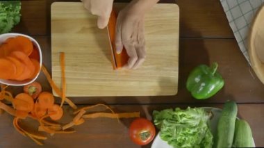 Salata sağlıklı yemek yapma ve mutfakta kesme tahtası üzerinde havuç doğrama kadın baş üstten görünüm.