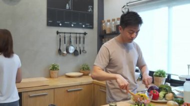 Asya adam mutfakta yiyecek salata hazırlayın. Güzel mutlu Asya çift mutfakta yemek vardır. Genç Asyalı Çift evde kalırken romantik zamanım. Çift yaşam tarzı, ev concept.