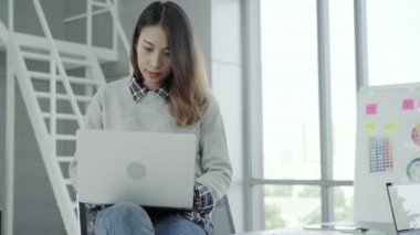 Profesyonel Asya işkadını laptop yolu ile onun ofisinde çalışıyor. Taşınabilir bilgisayar aygıt modern işyerinde otururken Genç Asyalı kadın Yöneticisi'ni kullanma.