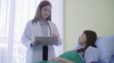 Genç Asyalı doktor kadın hasta yatağında panosuna kadın hasta için bilgi tedavi göster. Tıp, yaş, sağlık ve insan kavramı.