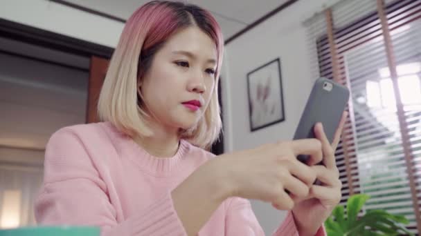 Vacker Asiatisk Kvinna Med Smartphone Liggande Skrivbordet Hennes Vardagsrum Lycklig — Stockvideo