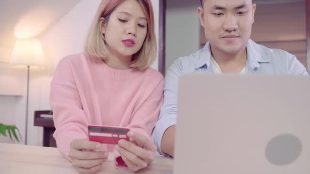 年轻的亚洲家庭夫妇使用笔记本电脑讨论新闻或做网上购物一起坐在办公桌上周末一起 认真的男人和女人浏览网页搜索新的销售优惠 — 图库视频影像