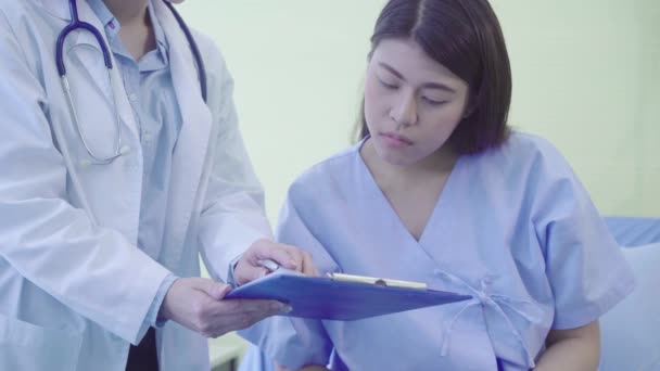 美丽聪明的亚洲医生和病人讨论和解释一些与剪贴板在医生的手 而留在病人的床在医院 医疗保健理念 — 图库视频影像