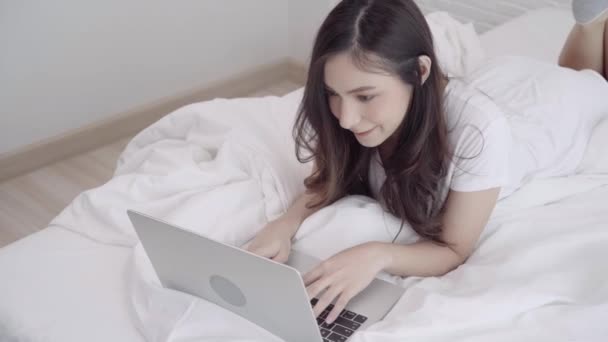 아시아 여자는 그녀의 침실에서 침대에 컴퓨터 노트북을 집에서 온라인으로 구매입니다 — 비디오
