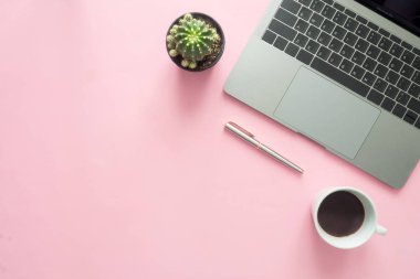 Ofis Masası adlı kullanıcının alanı - düz çalışma sıcak kahve Kupası, dizüstü bilgisayar, kalem ve bitki kopya alanı pastel renk arka plan üzerinde modern çalışma alanının en iyi görünümü yatırın. Pembe renk arka plan çalışma Resepsiyon kavramı.