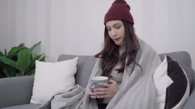 Güzel çekici Asyalı kadın kanepe üzerinde yalan ne zaman sıcak bir fincan kahve ya da çay tutarken evde oturma odasında rahatlayın. Noel ve yeni yıl tatilleri kavramı yaşam tarzı kadınlar evde.