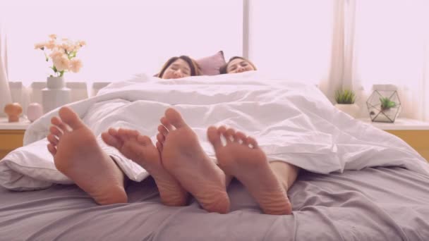 美丽快乐的亚洲女同性恋夫妇或朋友穿着睡衣听音乐和移动脚后 在卧室的床上的节奏在家里 生活方式同性恋同志夫妇放松在家的概念 — 图库视频影像