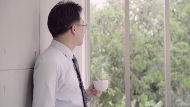 慢动作 亚洲微笑的商人喜欢喝温咖啡站在办公室放松 商务男士在办公室工作时放松身心 — 图库视频影像