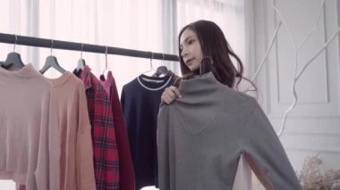 Ev dolap veya soyunma giyim mağazası. Evde dolap veya mağaza içinde onun moda kıyafet giysiler seçmek karışık yarış Asya ve beyaz genç kadın. Kız ne kazak giymeyi düşünüyorum.