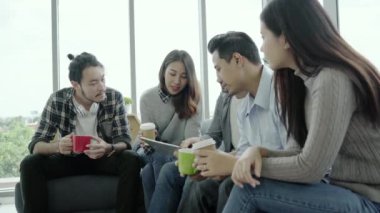 Kahve bardakları tutarak ve ofisinde kanepede oturan tablet ile Toplantı fikirleri tartışmak gençler grup takım çeşitliliği çok ırklı yaratıcı ekibi. Yaratıcı office anda kahve molası.