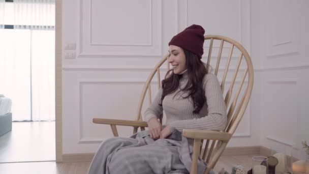 若いアジアの女性は 彼女のリビング ルームを自宅で灰色の毛布に包まれて椅子に座って 冬とクリスマス祭彼女のカップルから贈り物を得るの美しい女性 — ストック動画