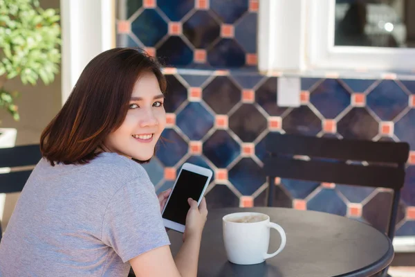 Iloinen Aasialainen Nuori Nainen Istuu Kahvilassa Juomassa Kahvia Käyttämällä Älypuhelinta — kuvapankkivalokuva
