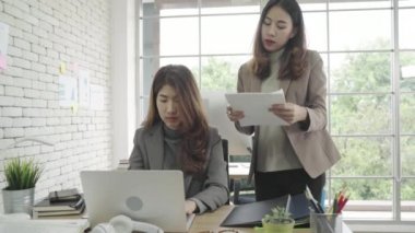 Smart casual kadında çekici akıllı Asya iş ofis masasında onun kızgın Yöneticisi ayakta kızgın atma kağıtları süre masasında otururken çalışma üstünde laptop giymek. Kadın ofis kavramı iş. 