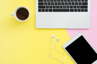 Ofis Masası adlı kullanıcının alanı - düz çalışma laptop, kahve fincanı, kulaklık ve sahte pastel arka plan tablete kadar üstten görünüm kopya alanı çalışma alanı yatırın. Pastel pembe sarı renk arka plan boşluk kavramı