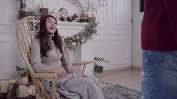 若いアジアの女性は 彼女のリビング ルームを自宅で灰色の毛布に包まれて椅子に座って 冬とクリスマス祭彼女のカップルから贈り物を得るの美しい女性 — ストック動画
