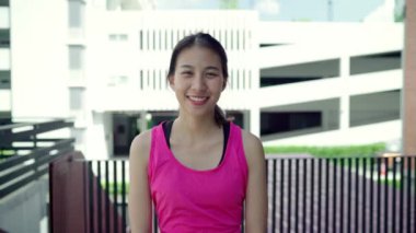 Yavaş hareket - sağlıklı güzel genç Asyalı atlet kadın gülümseyerek ve kentsel şehir sokakta çalıştırdıktan sonra kameraya bakarak mutlu hissediyor. Yaşam tarzı uygun ve etkin kadınların şehir konsepti egzersiz.
