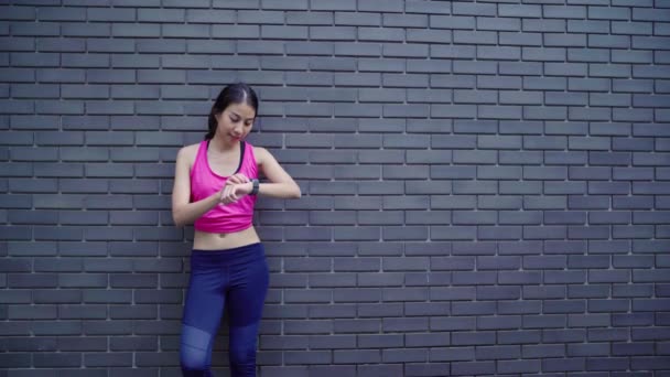 健康的な美しい若いアジア選手女性設定と都市で実行中のスマートな腕時計で心拍数のモニターを探しているの進行状況を確認します 市のコンセプトのライフ スタイルの女性運動 — ストック動画