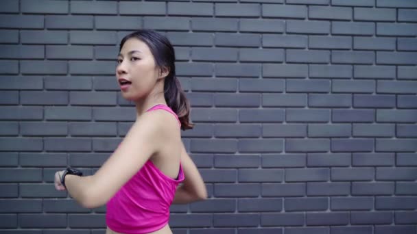 健康的な美しい若いアジア選手女性設定と都市で実行中のスマートな腕時計で心拍数のモニターを探しているの進行状況を確認します 市のコンセプトのライフ スタイルの女性運動 — ストック動画
