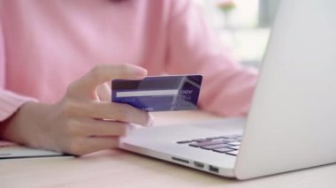 Güzel Asyalı kadın istimal bilgisayar ya da dizüstü evde oturma odasında masasında oturan giyim kazak sırasında kredi kartıyla alışveriş online satın alma. Yaşam tarzı kadına ev concept.