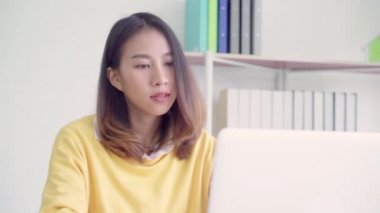 Asyalı kadın çalışma dizüstü evde oturma odasında masa üzerinde gülümseyen güzel genç. Asya iş kadını defter belge finans ve hesap makinesi ev ofis yazma. Ev concept anda zevk.