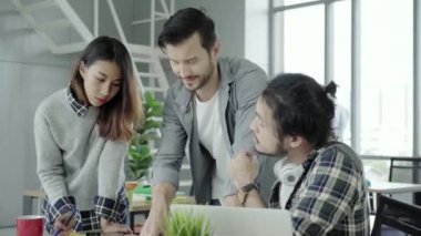 Grup raslantı giyimli iş adamları kızgın menajeri kızgın atma kağıtları ofis masasında duran süre masasında otururken dizüstü bilgisayarda çalışan akıllı giyim fikirleri tartışmak.