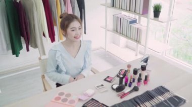 Güzellik blogger video kayıt için kamera önünde oturan güzellik kozmetik mevcut. Gözden geçirme makyaj eğitimi için sosyal ağ Internet tarafından canlı video yayını iken güzel Asyalı kadın kullanım kozmetik.