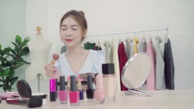 Güzellik blogger video kayıt için kamera önünde oturan güzellik kozmetik mevcut. Gözden geçirme makyaj eğitimi için sosyal ağ Internet tarafından canlı video yayını iken güzel Asyalı kadın kullanım kozmetik.