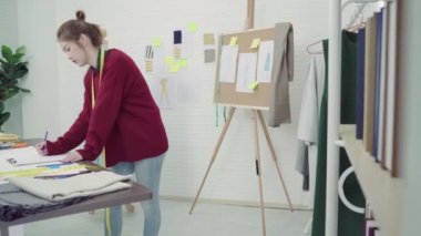 Kalem kullanarak ve atölye stüdyoda çalışırken gazetede arıyor Genç Asyalı kadın moda tasarımcısı çizim.