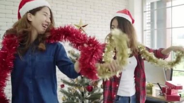 Yavaş hareket - mutlu Asyalı kadınlar Noel partisi office arkadaşlarıyla kutlamak. Erkek yeni yıl ve Noel Festivali birlikte kutluyor. Grup Santa şapka dans ofiste güzel insan.
