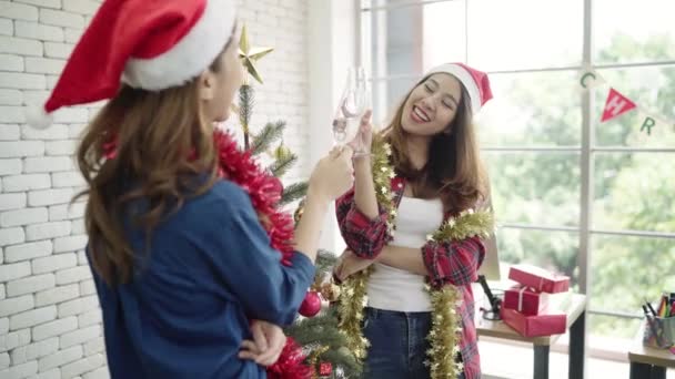 幸せなアジア女性は 彼女の事務所でお友達とクリスマス パーティーを祝うため 女性はクリスマス祭と新年を一緒に祝います 女の子は事務所でサンタ帽子お酒を着用します — ストック動画