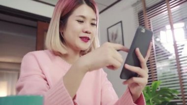 Genç Asyalı kadın Danışma onun oturma odasında yatarken Smartphone kullanarak. Mutlu erkek okuma, mesajlaşma ve evde online satın alma telefon mesaj attığın için kullanın. Yaşam tarzı kadına ev concept.