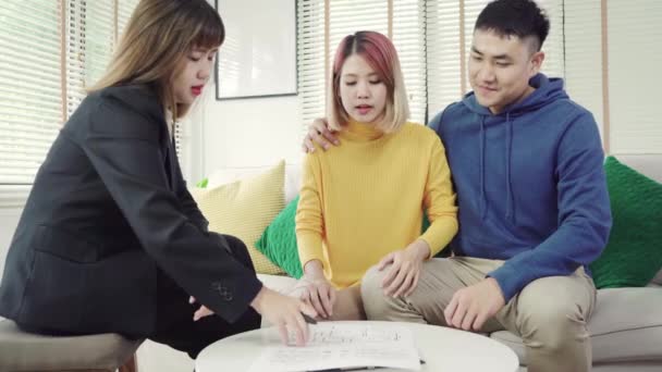 快乐的亚洲夫妇和房地产经纪人 开朗的年轻人与妻子一起坐在办公桌前签了一些文件 买新房房地产 签署良好条件合同 — 图库视频影像