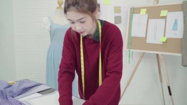 Profesyonel güzel Asyalı kadın moda kumaş çizimler ile çalışma ve stüdyoda giyim tasarım çizim tasarımcı. Yaşam tarzı kadın kavramı çalışma.
