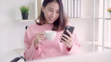 Güzel akıllı iş smartphone kullanarak ve yaratıcı ofiste tabloda otururken sıcak fincan kahve içme akıllı rahat kıyafet içinde Asyalı kadın. Yaşam tarzı kadın ofis kavramı çalışma.