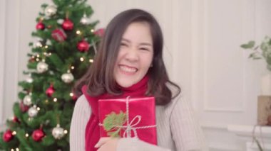 Noel hediyeleri Noel Festivali evde onun oturma odasına kamera için gülümseyen holding neşeli mutlu Genç Asyalı kadın. Yaşam tarzı kadın kutlamak Noel ve yeni yıl kavramı.