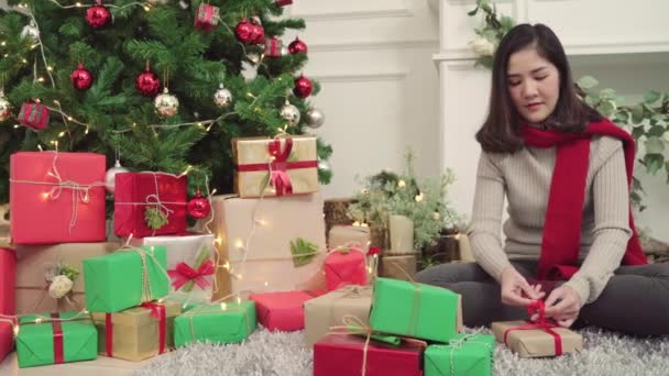 快乐快乐的年轻亚洲女人在圣诞节期间装饰着家里的客厅 她收拾圣诞礼物 生活方式女性庆祝圣诞节和新年概念 — 图库视频影像
