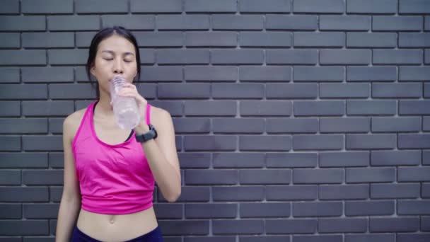 健康美丽的年轻亚洲跑步女子饮水 因为在城市街头跑步后感到疲惫 生活方式适合和活跃的妇女锻炼在城市概念 — 图库视频影像
