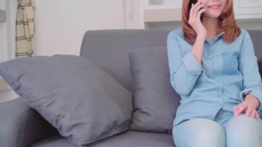 Akıllı telefon kanepede yatan arkadaşlarınızla konuşurken güzel çekici genç gülümseyen Asyalı kadın portresi ne zaman evde oturma odasında gevşeyin. Ev concept zaman yaşam tarzı kadınlar enjoying.