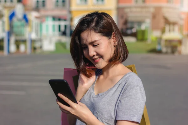 Vakker Ung Shopaholisk Asiatisk Kvinne Som Bruker Smarttelefon Snakke Mens – stockfoto