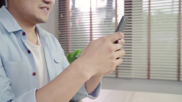 Onun Oturma Odası Masasında Yatarken Smartphone Kullanarak Asya Delikanlı Mutlu — Stok video