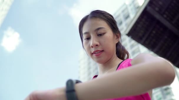 健康美丽的年轻亚洲运动员设置和检查进展看心率监测仪智能手表 而在城市运行 城市概念中的生活方式女性锻炼 — 图库视频影像