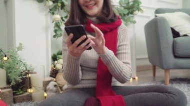 Onu oturma odasında evde Noel Festivali sosyal medya kontrol etmek için Smartphone kullanarak neşeli mutlu Genç Asyalı kadın. Yaşam tarzı kadın kavramı, Noel ve yeni yıl kutlama.