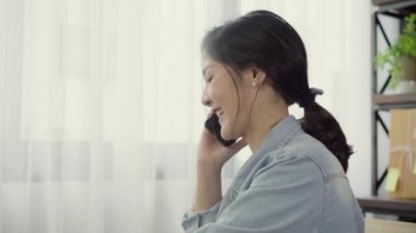 Güzel akıllı Asya genç girişimci iş kadın sahibi KOBİ online müşteri ve evde çalışan dizüstü kullanarak almak smartphone telefon kullanarak. Küçük işletme sahibi, ev ofis kavramı.