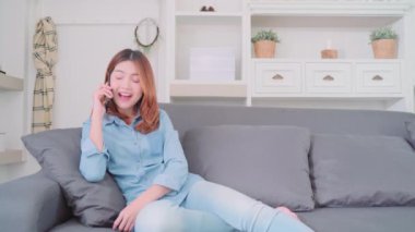 Akıllı telefon kanepede yatan arkadaşlarınızla konuşurken güzel çekici genç gülümseyen Asyalı kadın portresi ne zaman evde oturma odasında gevşeyin. Ev concept zaman yaşam tarzı kadınlar enjoying.